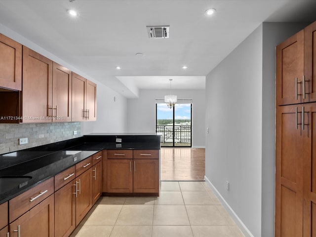 kitchen featuring an inviting chandelier, tasteful backsplash, light tile patterned flooring, hanging light fixtures, and dark stone counters