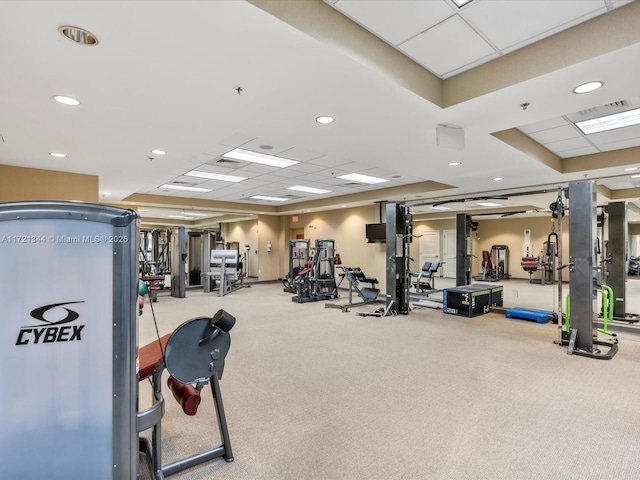 gym with a paneled ceiling and light carpet