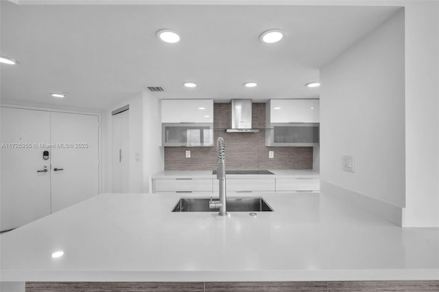 kitchen with white cabinets, backsplash, and wall chimney exhaust hood