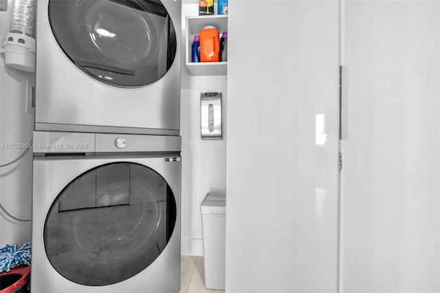 laundry room featuring stacked washer and dryer and light tile patterned flooring