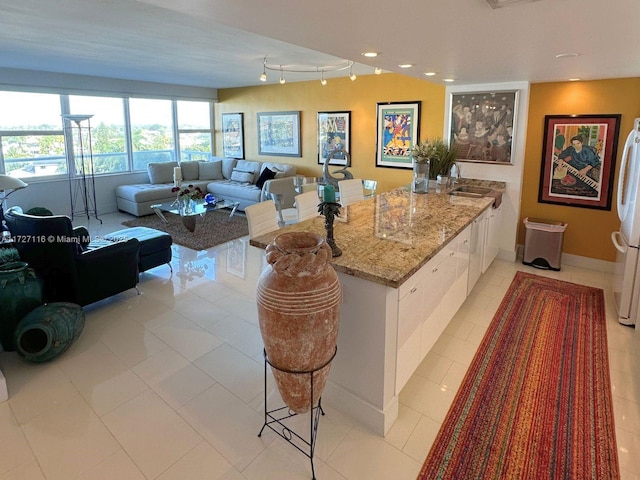 3300 NE 36th St Unit 605, Fort Lauderdale, FL 33308 - kitchen with a peninsula, a sink, white cabinets, track lighting, and light stone countertops
