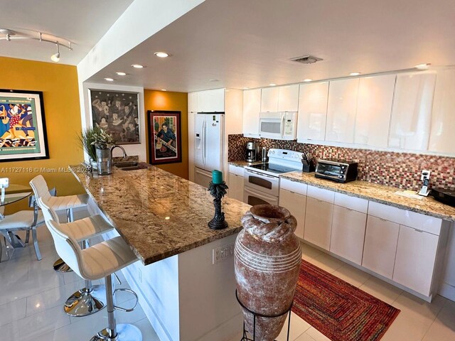 3300 NE 36th St Unit 605, Fort Lauderdale, FL 33308 - kitchen with white appliances, light tile patterned floors, a kitchen bar, a peninsula, and recessed lighting