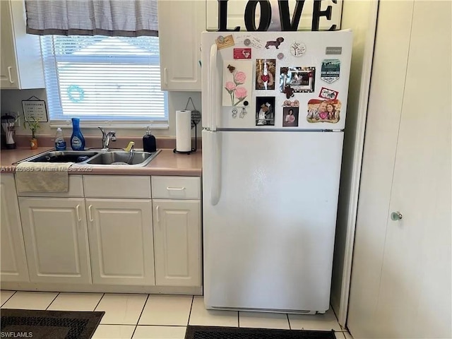 kitchen featuring white fridge, light tile patterned floors, white cabinets, and sink