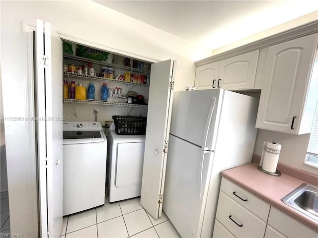 washroom with separate washer and dryer, light tile patterned floors, and sink