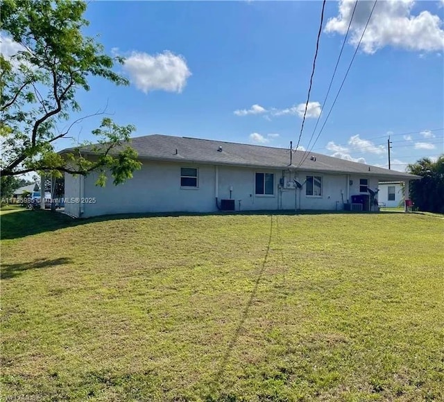 back of property featuring central AC unit and a lawn