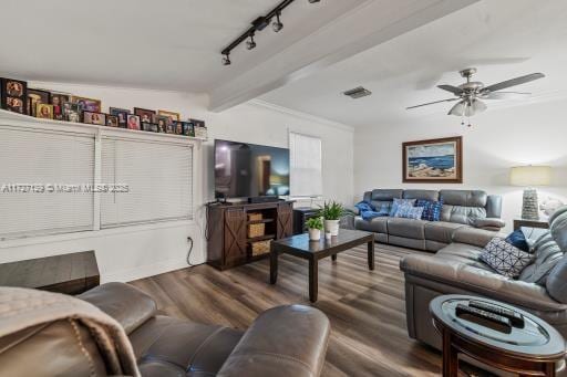 living room with ceiling fan, beam ceiling, dark wood-type flooring, ornamental molding, and rail lighting