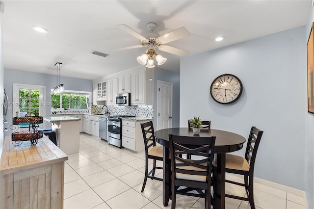 tiled dining room featuring ceiling fan and sink