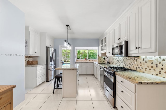 kitchen featuring stainless steel appliances, a kitchen bar, white cabinetry, and a center island