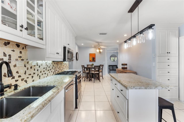 kitchen featuring white cabinetry, stainless steel appliances, backsplash, sink, and a center island