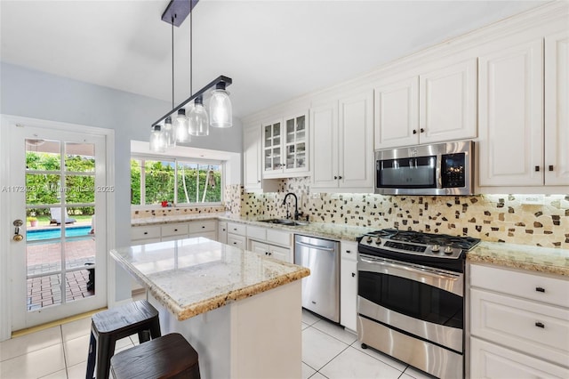 kitchen with white cabinets, a center island, stainless steel appliances, decorative backsplash, and sink