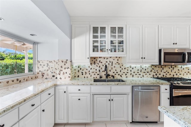 kitchen featuring tasteful backsplash, sink, light stone countertops, stainless steel appliances, and white cabinets