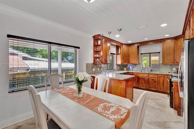 kitchen with kitchen peninsula, stainless steel refrigerator with ice dispenser, decorative light fixtures, ornamental molding, and light stone counters