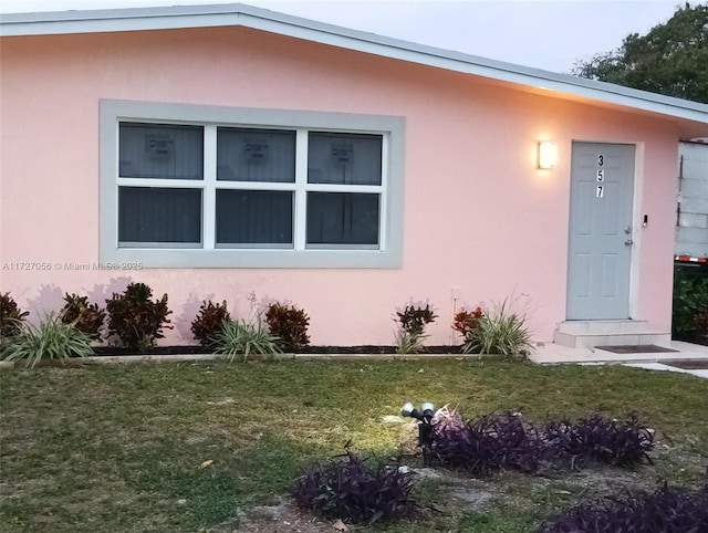 doorway to property featuring stucco siding and a yard