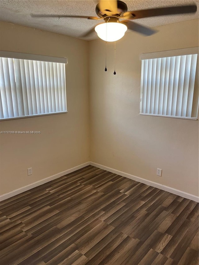 spare room featuring dark wood finished floors, ceiling fan, a textured ceiling, and baseboards