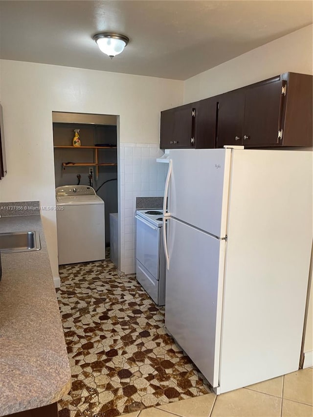 kitchen featuring washer / dryer, tile walls, white appliances, and a sink