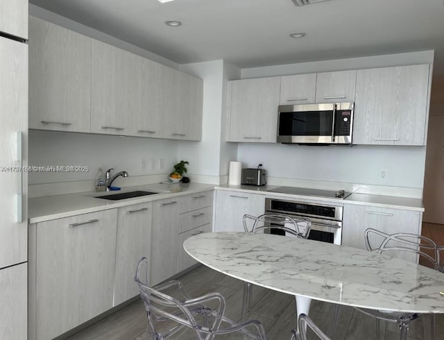 kitchen featuring sink, appliances with stainless steel finishes, a kitchen breakfast bar, and dark hardwood / wood-style flooring