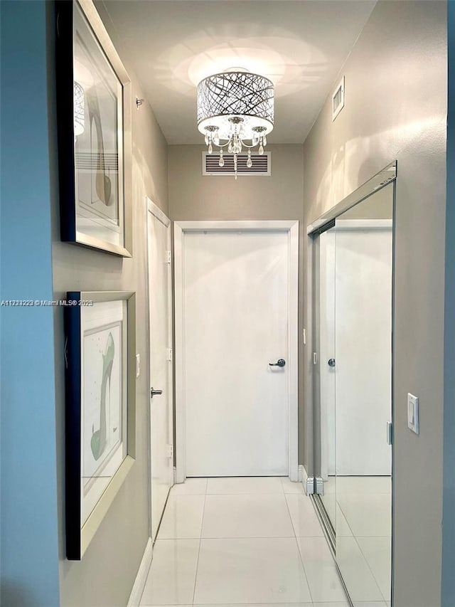 hall featuring light tile patterned floors and a chandelier