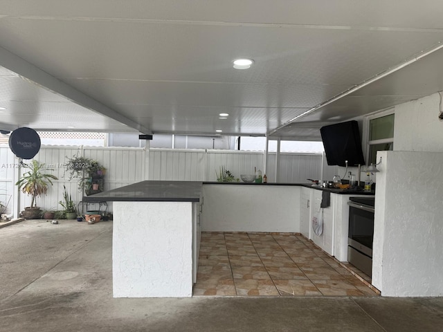 kitchen featuring white cabinetry, white refrigerator, kitchen peninsula, and stainless steel range with electric cooktop