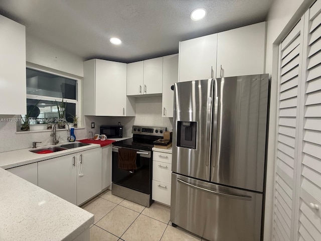 kitchen featuring light tile patterned floors, appliances with stainless steel finishes, sink, and white cabinetry