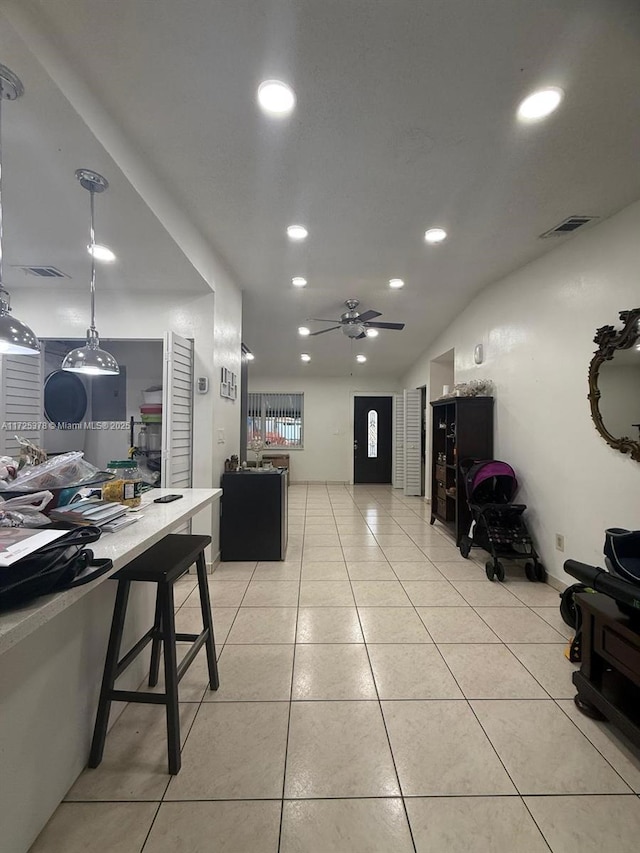 interior space featuring ceiling fan, decorative light fixtures, light tile patterned floors, and a breakfast bar area