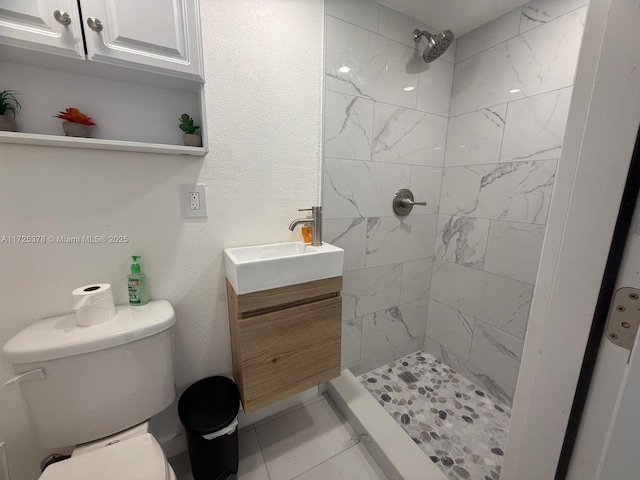 bathroom featuring toilet, a tile shower, and vanity