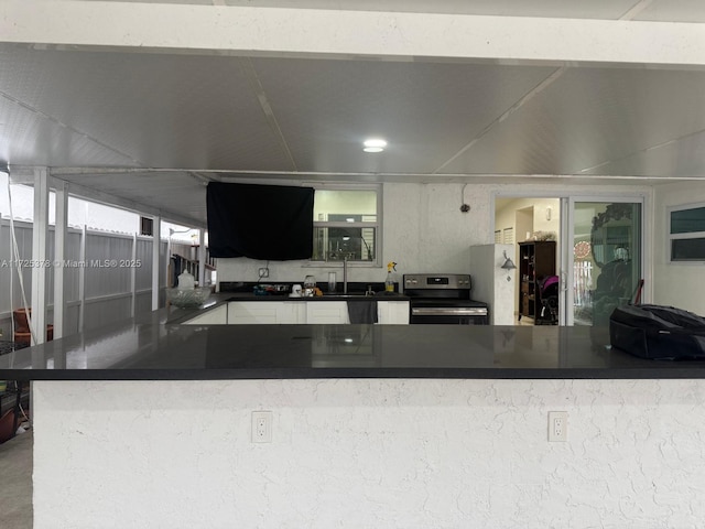 kitchen featuring stainless steel electric stove, kitchen peninsula, and sink