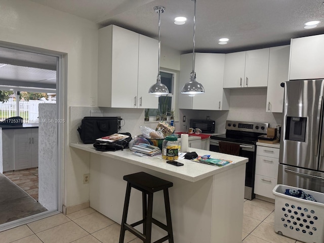 kitchen with appliances with stainless steel finishes, a kitchen bar, white cabinets, and decorative light fixtures