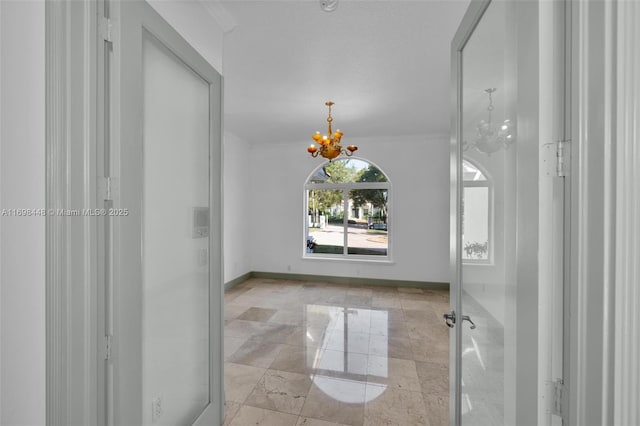 interior space with ornamental molding, a notable chandelier, and baseboards