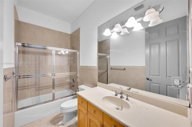 full bath featuring visible vents, toilet, tile patterned floors, combined bath / shower with glass door, and tile walls