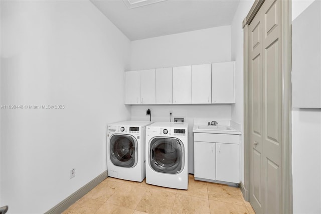 laundry area with cabinet space, light tile patterned floors, baseboards, washer and clothes dryer, and a sink