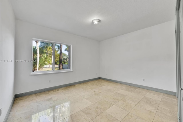 unfurnished room featuring a textured ceiling and baseboards