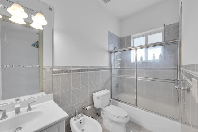 bathroom with toilet, vanity, tile walls, combined bath / shower with glass door, and wainscoting