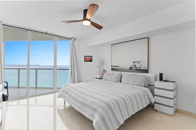 bedroom featuring multiple windows, a wall of windows, access to outside, and a water view