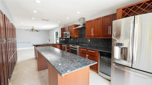 kitchen with sink, appliances with stainless steel finishes, wine cooler, kitchen peninsula, and wall chimney exhaust hood