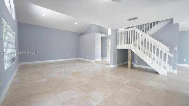 unfurnished living room with vaulted ceiling and a textured ceiling