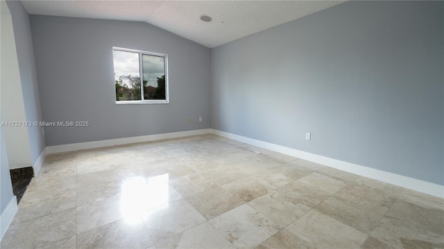 spare room with lofted ceiling and a textured ceiling