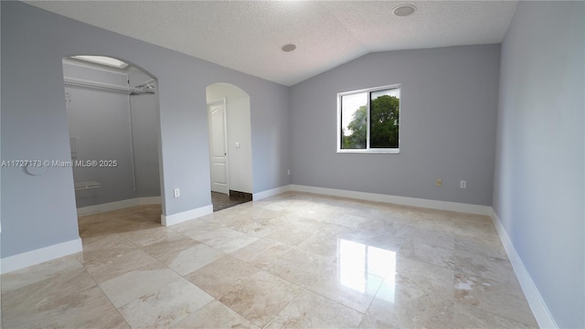 unfurnished bedroom featuring lofted ceiling and a textured ceiling