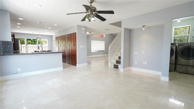 unfurnished living room featuring ceiling fan, washer and clothes dryer, and a textured ceiling