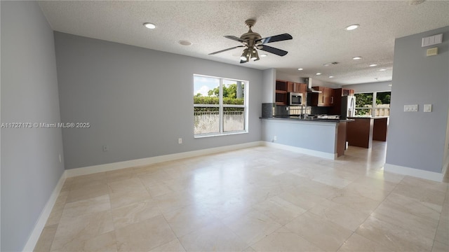 unfurnished living room with a textured ceiling, plenty of natural light, and ceiling fan