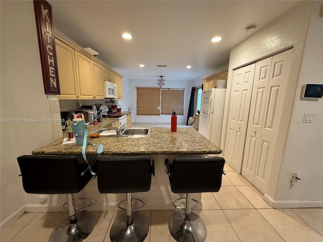 kitchen featuring light tile patterned floors, kitchen peninsula, a breakfast bar area, tasteful backsplash, and white appliances