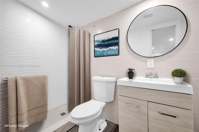 bathroom featuring a shower, tile walls, toilet, and vanity