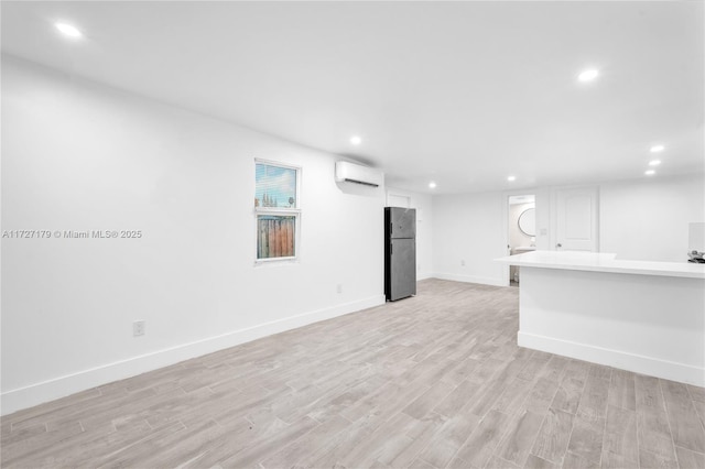 unfurnished living room with light hardwood / wood-style flooring and a wall mounted air conditioner