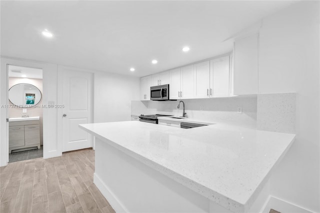 kitchen with light hardwood / wood-style flooring, white cabinets, kitchen peninsula, and sink