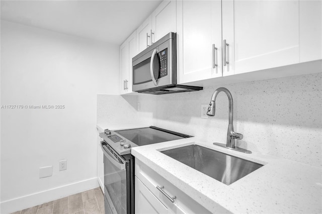 kitchen with light stone counters, white cabinets, appliances with stainless steel finishes, and tasteful backsplash