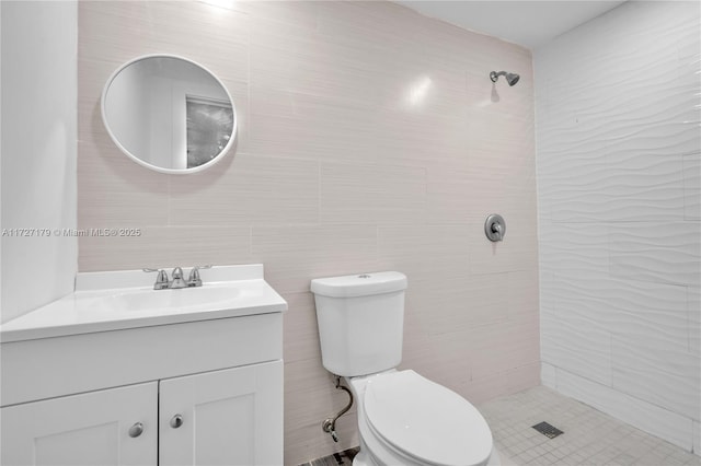 bathroom with tile walls, toilet, vanity, and a tile shower