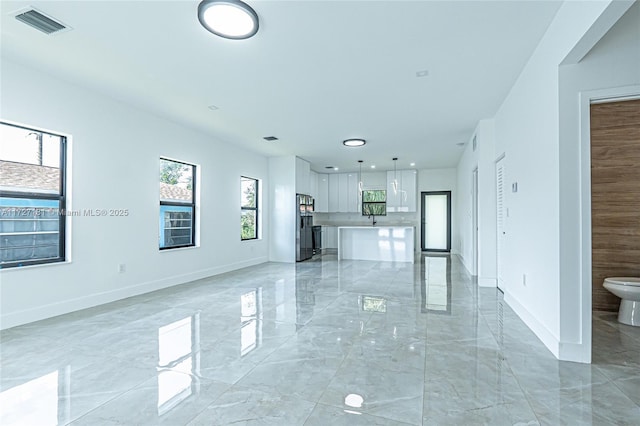 unfurnished living room with visible vents, baseboards, and marble finish floor