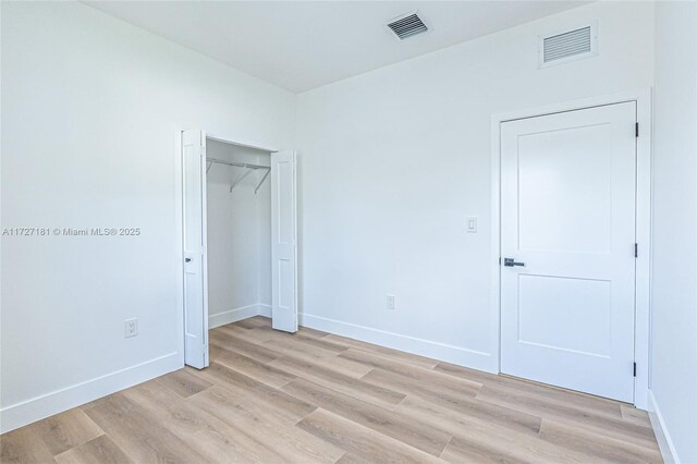 unfurnished bedroom with a closet and light hardwood / wood-style floors