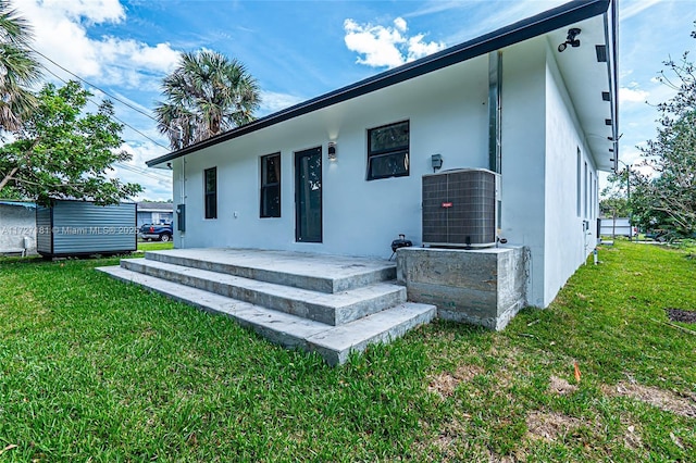 rear view of property featuring a yard and central air condition unit