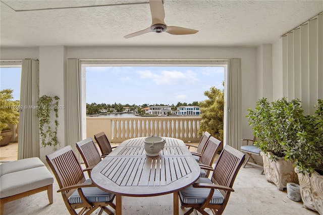 sunroom featuring a water view, ceiling fan, and plenty of natural light