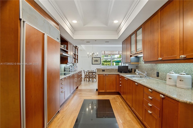 kitchen with pendant lighting, paneled built in refrigerator, sink, backsplash, and a raised ceiling